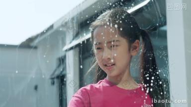 快乐的小女孩往玻璃上喷清洗剂